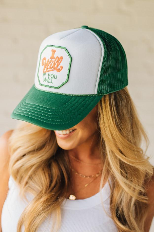 Blonde woman wearing a green mesh back trucker hat with white panel front, and a patch at the center that says "I Will If You Will" with red accent embroidery.