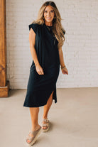 BLONDE WOMAN WEARING A BLACK ROUND NECK SHORT SLEEVE MIDI DRESS WITH SIDE SLIT.