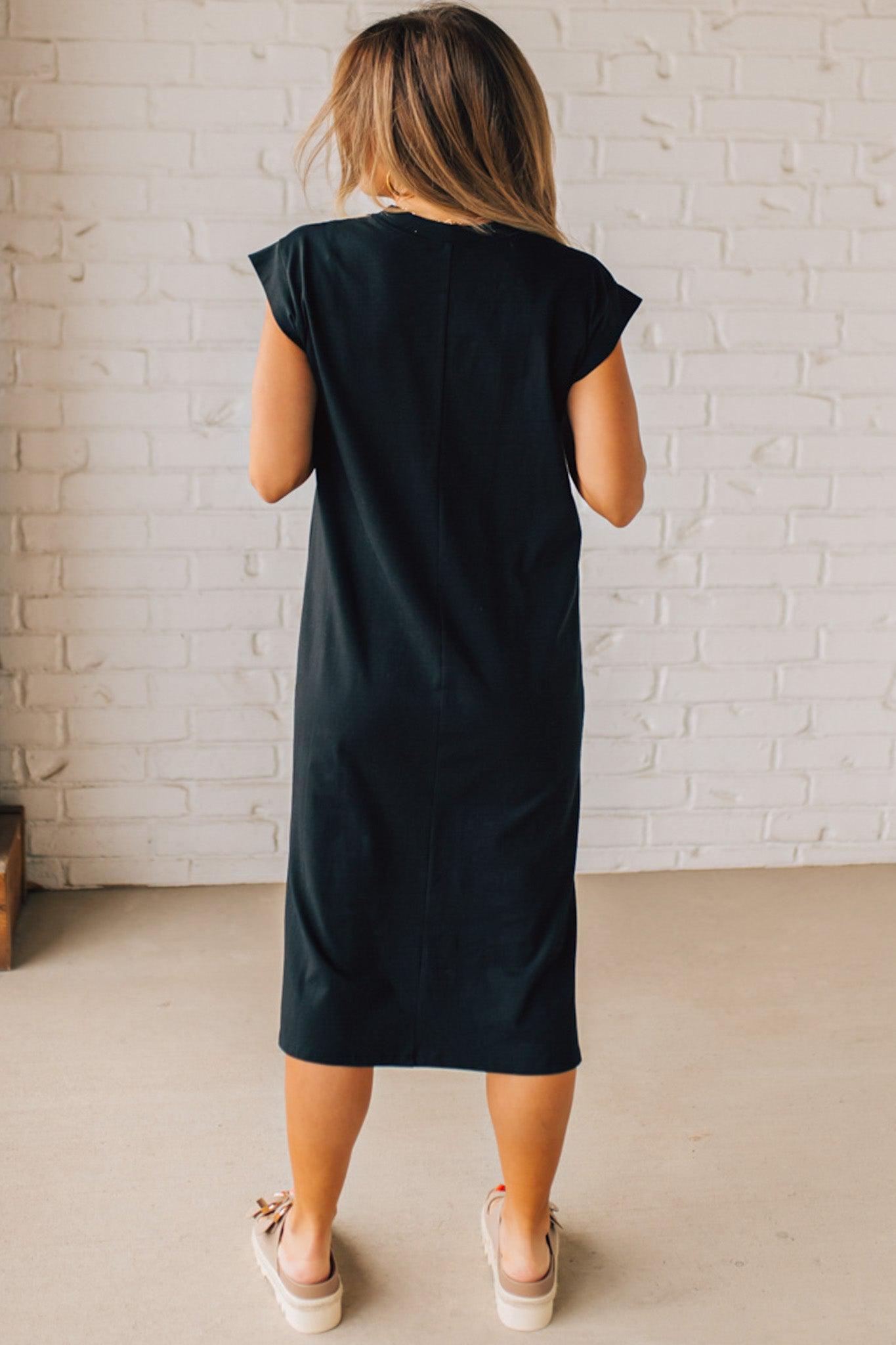 BLONDE WOMAN WEARING A BLACK ROUND NECK SHORT SLEEVE MIDI DRESS WITH SIDE SLIT.