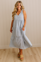 Woman wearing a light blue dress standing against a beige wall.