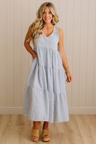 Woman wearing a light blue dress standing against a beige wall.