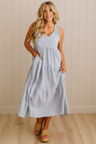 Woman wearing a light blue dress standing against a beige wall.