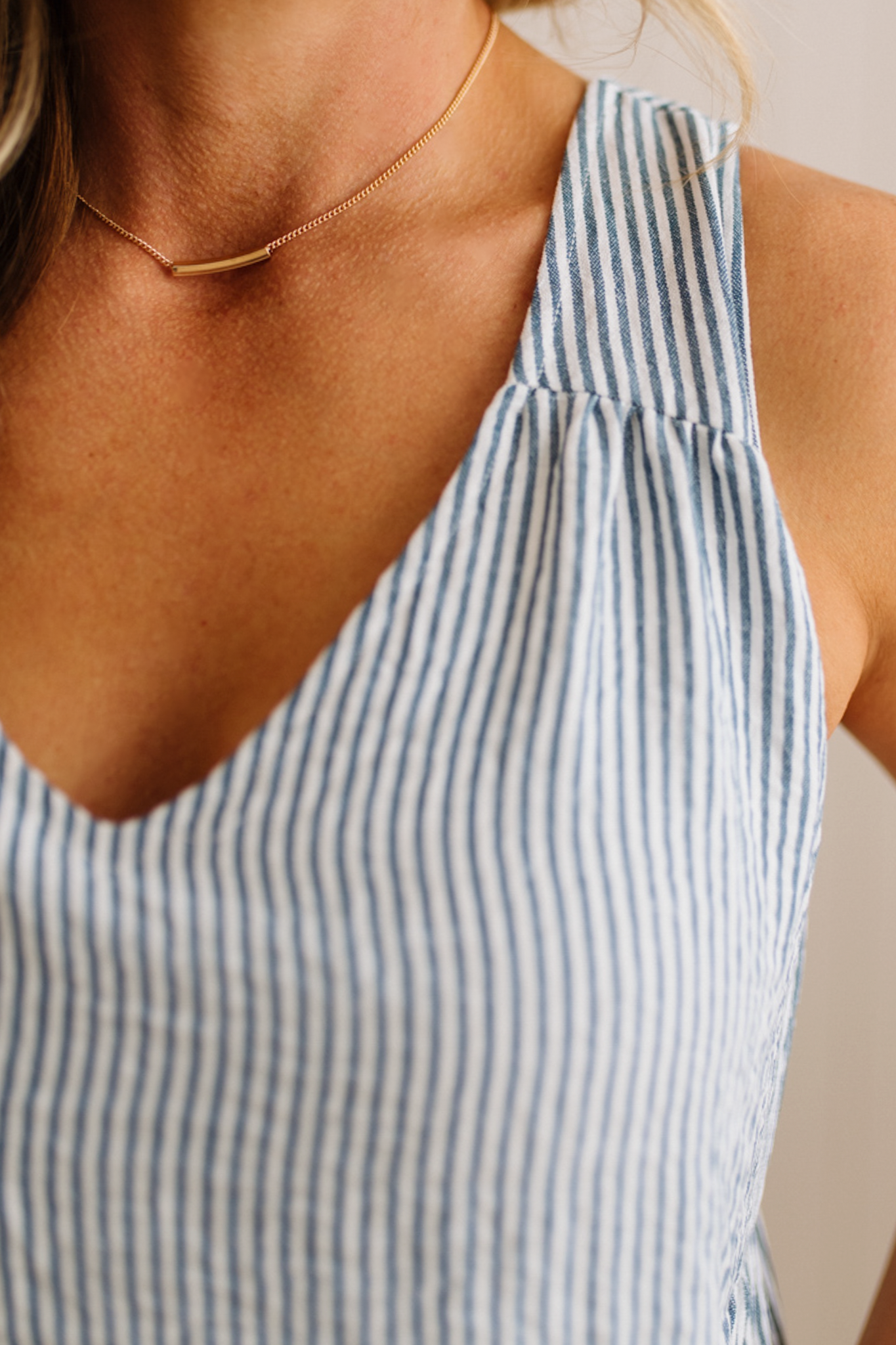 Close-up of a person wearing a blue and white striped dress with a neutral background