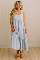 Woman wearing a light blue dress standing against a beige wall.