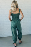 Women wearing olive green jumpsuit with elastic waist and front zipper.