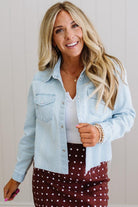 Woman wearing a light blue denim jacket over a white top and polka dot skirt.