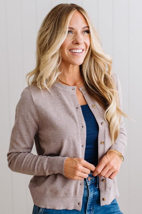 Blonde woman in dark jeans modeling in bright studio wearing a heather mocha cardigan with brown button front.