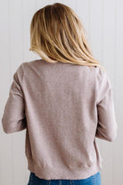 Blonde woman in dark jeans modeling in bright studio wearing a heather mocha cardigan with brown button front.
