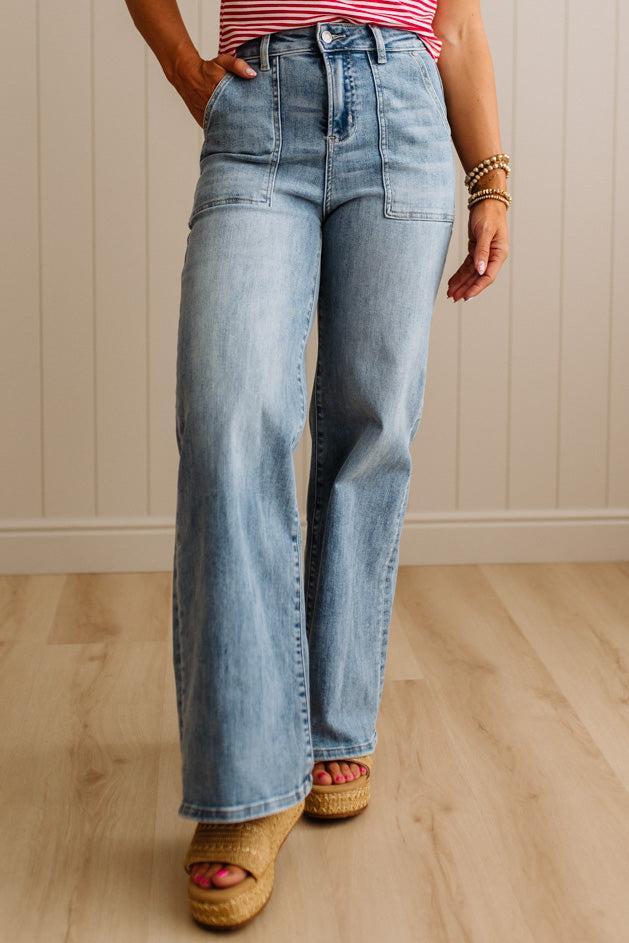 Person wearing blue jeans and a striped shirt against a beige wall.
