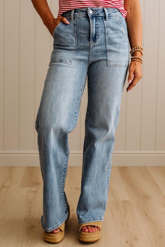 Person wearing light blue jeans and a striped shirt against a neutral wall.