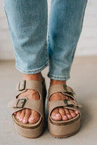 Beige sandals worn with light blue jeans on a neutral background