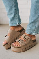 Beige platform sandals worn with light blue jeans on a neutral background