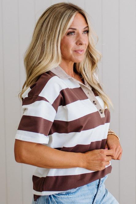 Woman wearing a brown and white striped shirt with a neutral background