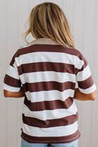 Person wearing a brown and white striped shirt against a light wooden panel background