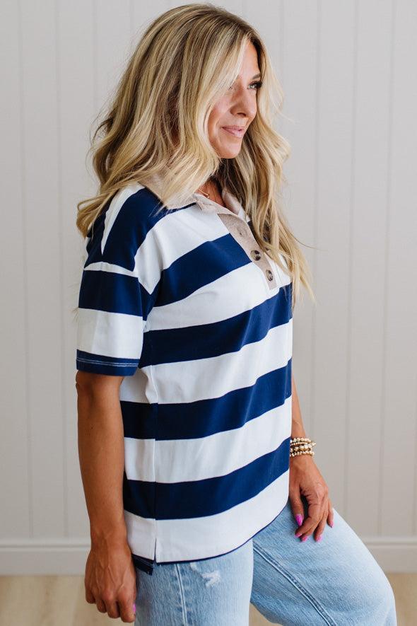 Woman wearing a navy and white striped shirt with light blue jeans against a neutral background