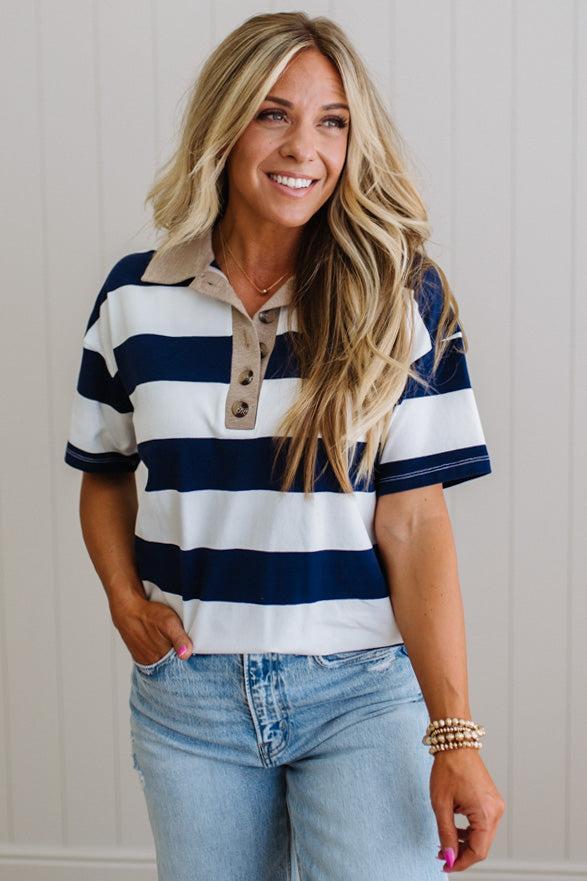 Woman wearing a navy and white striped shirt with blue jeans against a neutral background
