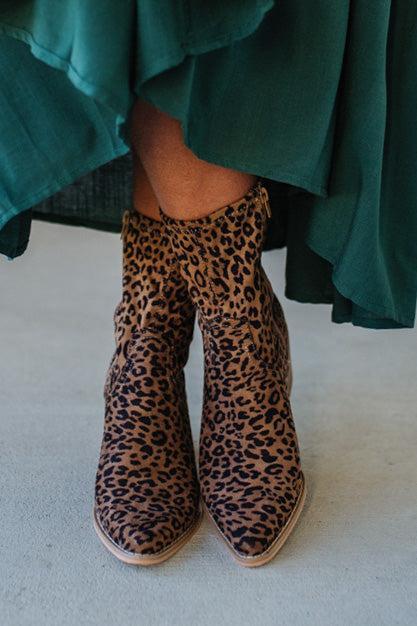 Person Wearing Leopard print, side zipper Sleek Ankle Hugging Booties with a green skirt.