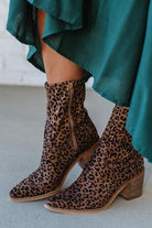 Person Wearing Leopard print, side zipper Sleek Ankle Hugging Booties with a green skirt.