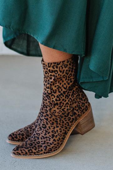 Person Wearing Leopard print, side zipper Sleek Ankle Hugging Booties with a green skirt.