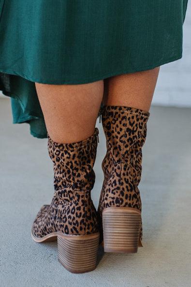Person Wearing Leopard print, side zipper Sleek Ankle Hugging Booties with a green skirt.