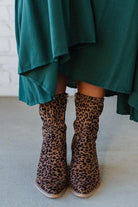 Person Wearing Leopard print, side zipper Sleek Ankle Hugging Booties with a green skirt.