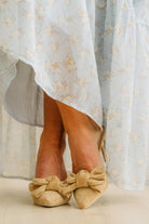Beige shoes with large bows worn with a light floral dress.