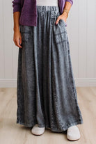 WOMAN IN A BRIGHTLY LIT STUDIO WEARING A TANK WITH CHAMBRAY ELASTIC WAIST POUCH POCKET WIDE LEG CULOTES PANTS IN GREY.