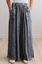 WOMAN IN A BRIGHTLY LIT STUDIO WEARING A TANK WITH CHAMBRAY ELASTIC WAIST POUCH POCKET WIDE LEG CULOTES PANTS IN GREY.