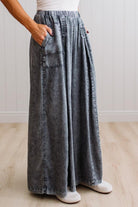 WOMAN IN A BRIGHTLY LIT STUDIO WEARING A TANK WITH CHAMBRAY ELASTIC WAIST POUCH POCKET WIDE LEG CULOTES PANTS IN GREY.