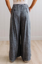 WOMAN IN A BRIGHTLY LIT STUDIO WEARING A TANK WITH CHAMBRAY ELASTIC WAIST POUCH POCKET WIDE LEG CULOTES PANTS IN GREY.