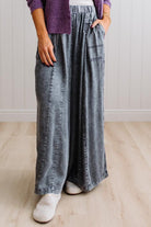 WOMAN IN A BRIGHTLY LIT STUDIO WEARING A TANK WITH CHAMBRAY ELASTIC WAIST POUCH POCKET WIDE LEG CULOTES PANTS IN GREY.