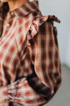 Plaid shirt with ruffled collar and cuffs on a blurred background