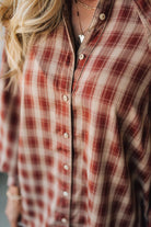 Close-up of a person wearing a red and brown plaid shirt.