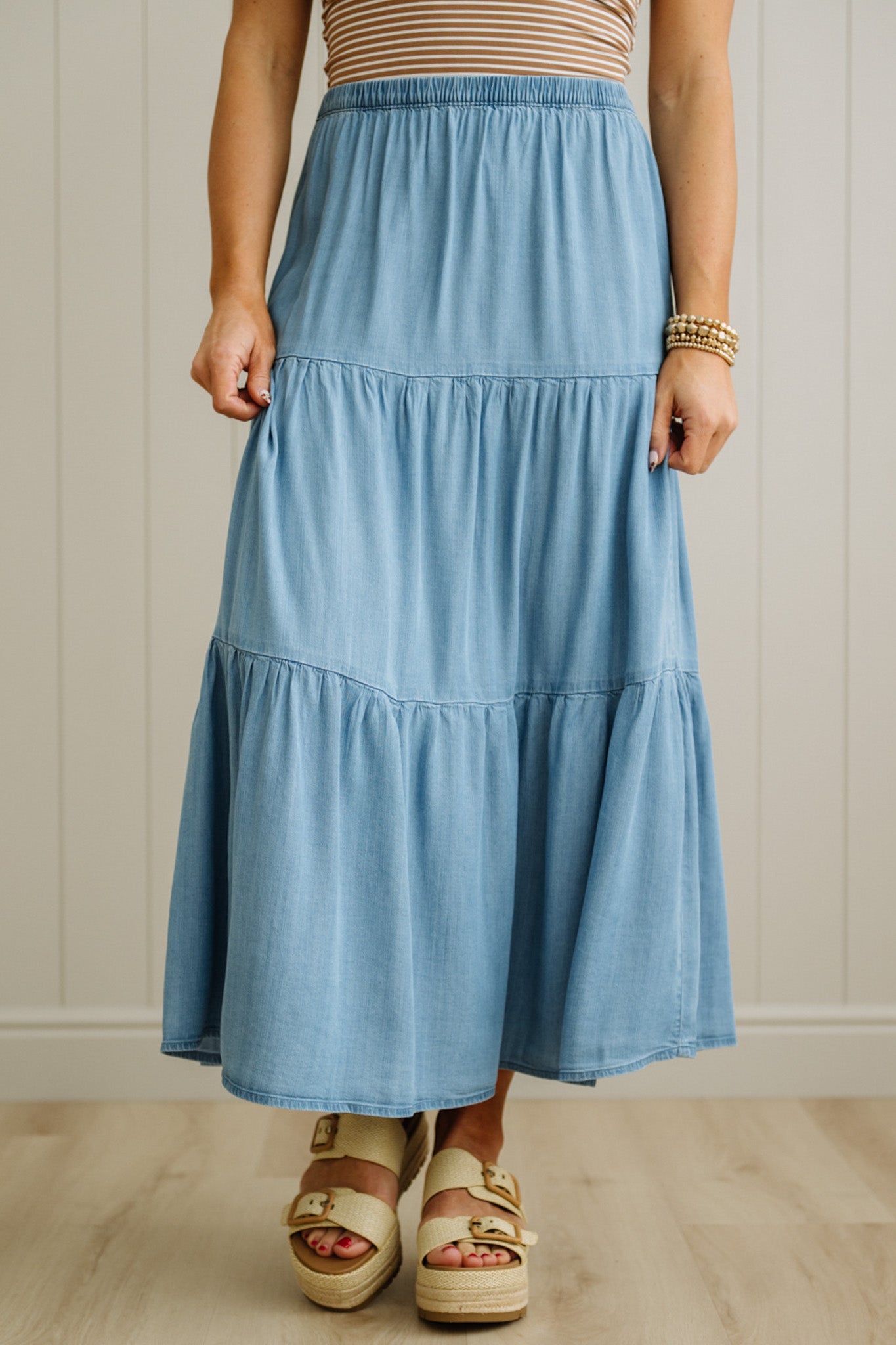Person wearing a blue tiered skirt with a neutral background