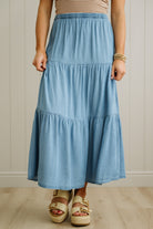 Person wearing a blue tiered skirt with a neutral background