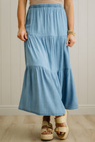 Person wearing a blue tiered skirt with a neutral background
