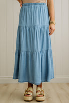 Person wearing a blue tiered skirt with a neutral background