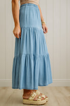 Person wearing a blue tiered skirt with a neutral background