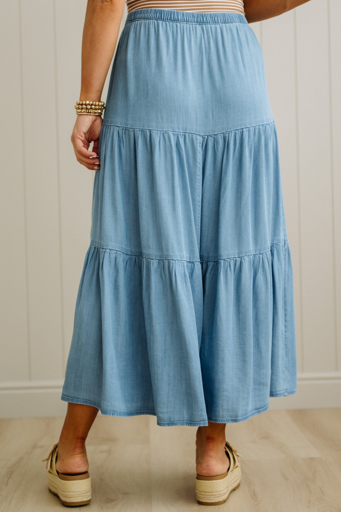 Person wearing a blue tiered skirt against a neutral background