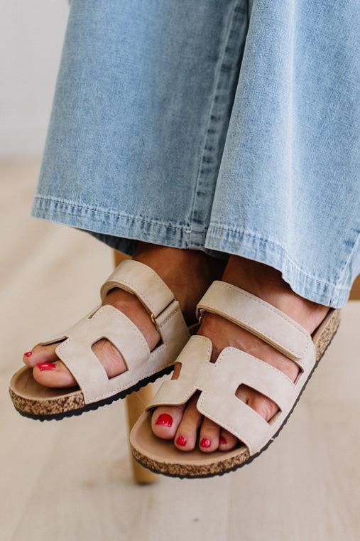 Beige sandals worn with light blue jeans on a neutral background