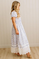 White dress with blue floral pattern and lace trim on a wooden floor.