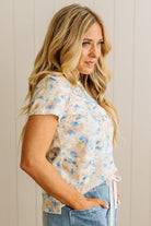 Woman wearing a floral blouse and jeans against a neutral background