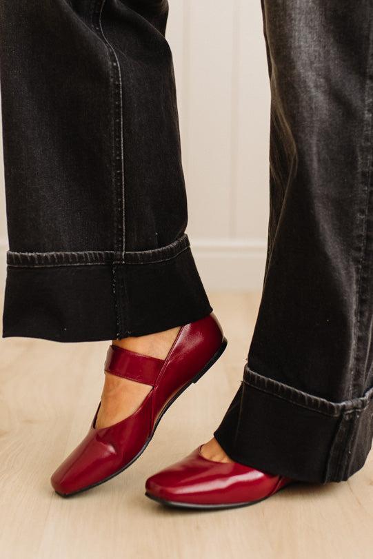 Red loafers worn with black jeans on a neutral background