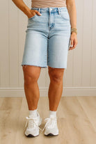 Person wearing light blue denim shorts and white sneakers indoors.
