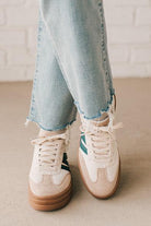 Girl modeling a pair of cream and dark green platform sneakers