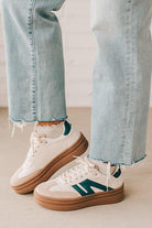 Girl modeling a pair of cream and dark green platform sneakers