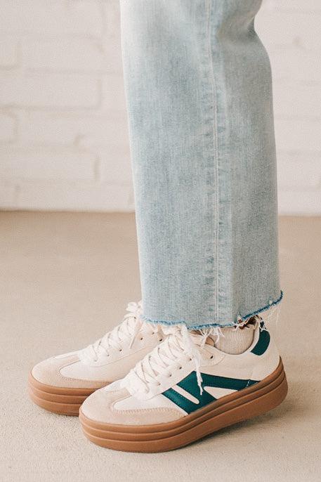 Girl modeling a pair of cream and dark green platform sneakers