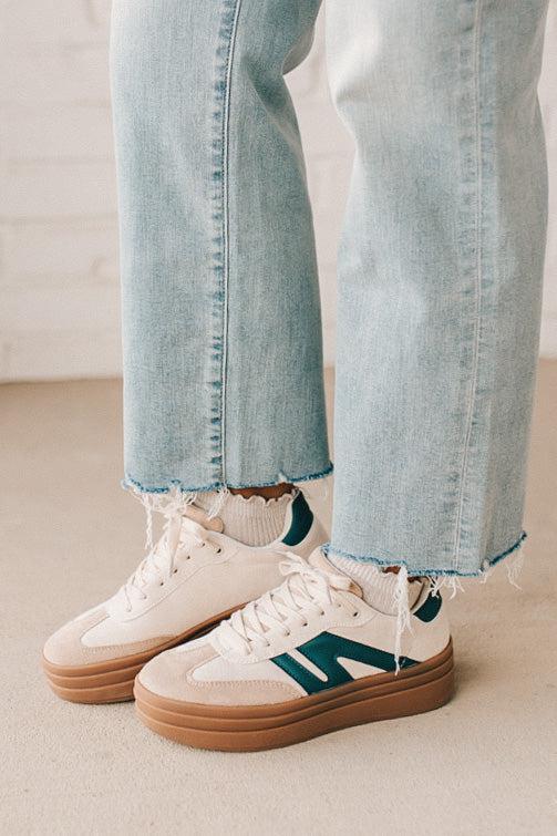 Girl modeling a pair of cream and dark green platform sneakers