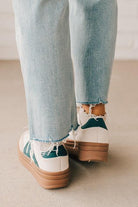 Girl modeling a pair of cream and dark green platform sneakers