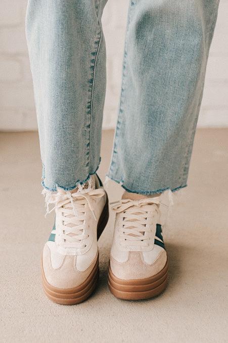 Girl modeling a pair of cream and dark green platform sneakers